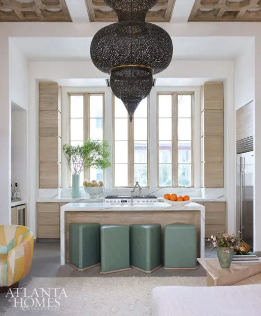 Kitchen island with green stools, marble countertops, and ornate pendant lights.