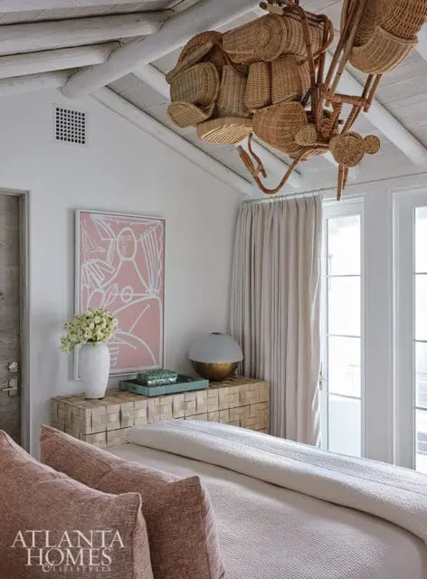 Bedroom with pink abstract art, rattan chandelier, and wood dresser