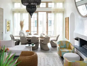 Living and dining room with sectional sofa, oval dining table, wicker chairs, and colorful