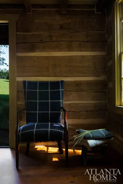 Armchair with dark blue plaid upholstery in a log cabin room with wooden floors.