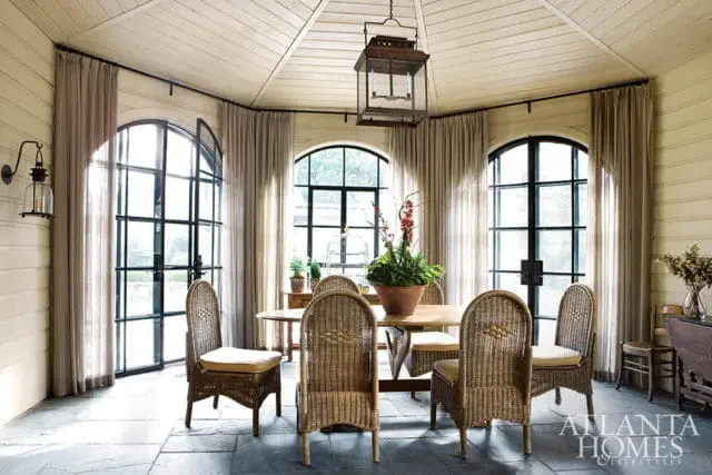 Dining room with wicker chairs, arched windows, and a large lantern.