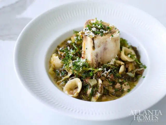 Bone marrow with pasta and greens, sprinkled with cheese and herbs.
