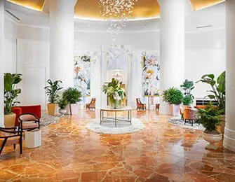 Lobby with marble floors, tall white columns, floral artwork, and modern seating