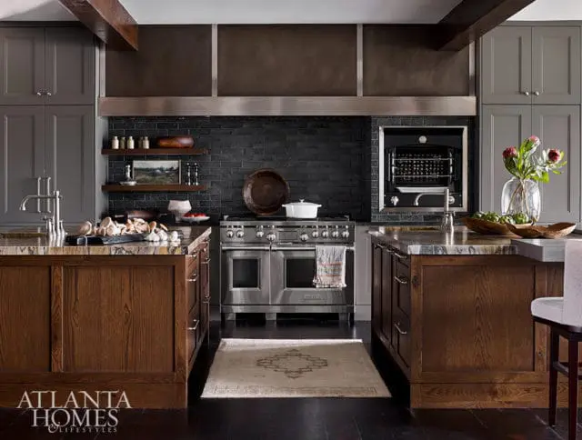 Gray cabinets, dark brick backsplash, and stainless steel range in a luxury kitchen.