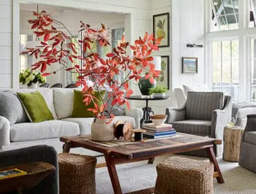Living room with white shiplap walls, sectional sofa, striped armchairs, and a rustic coffee table