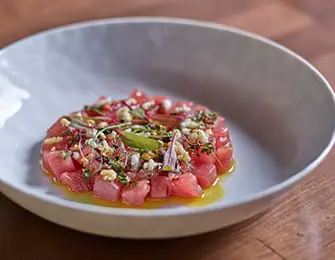 Diced tuna tartare with herbs and dressing in a white bowl
