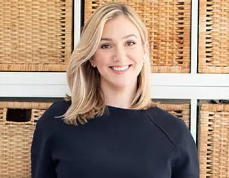 Brittany Forsling smiling in front of woven storage baskets.
