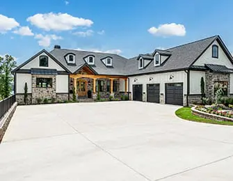 Modern farmhouse with white siding, stone accents, and a large concrete driveway.