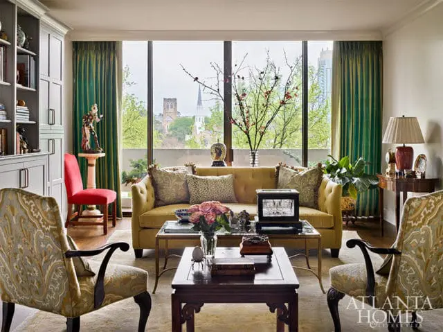 Yellow tufted sofa with patterned pillows, flanked by ornate chairs.