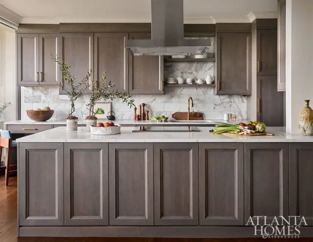 Gray kitchen island with marble countertop, gray cabinets, and marble backsplash.