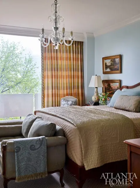 Bedroom with light blue walls, plaid curtains, and a bed with a quilted coverlet.