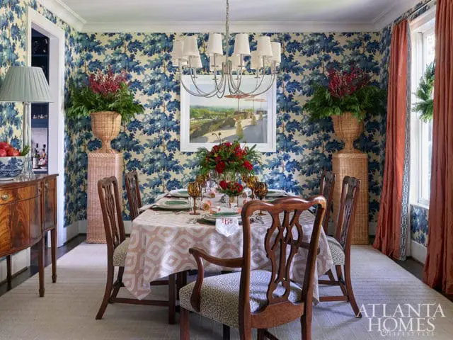 Dining room with blue floral wallpaper, a table set for six, and a wooden buffet.