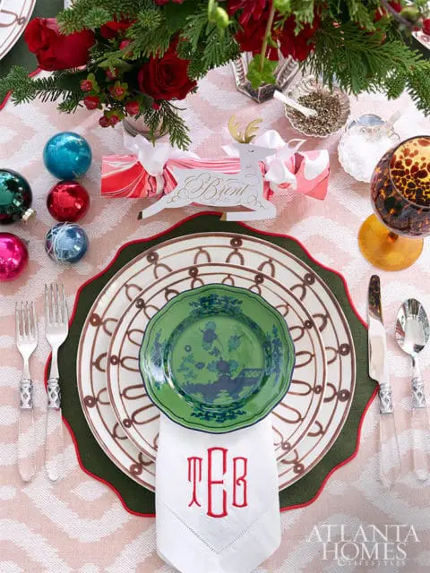 Table setting with green and white plates, red monogrammed napkin, and floral centerpiece