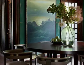 Dining room with dark wood table, green walls, and abstract landscape art