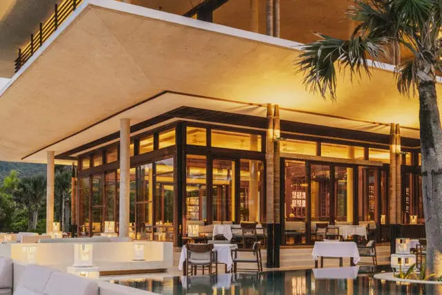 Restaurant with large glass windows, wooden accents, and tables set for dining.