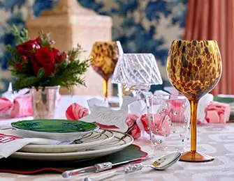 Table setting with leopard print wine glasses, floral arrangement, and stacked plates.