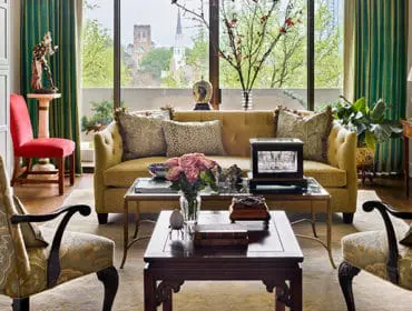 Living room with yellow tufted sofa, patterned armchairs, and dark wood coffee table.