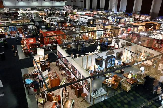Antique furniture and decor booths with people browsing at a market