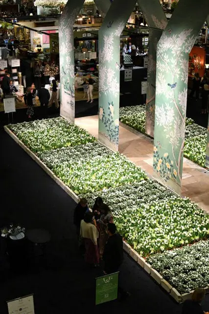 Hallway lined with white flowers and decorative pillars featuring floral and bird murals.