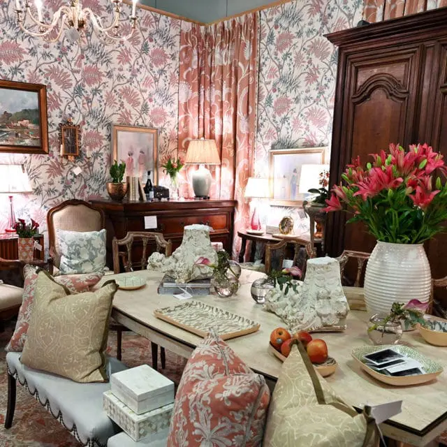 Dining room with floral wallpaper, ornate chandelier, and table set with decorative objects and