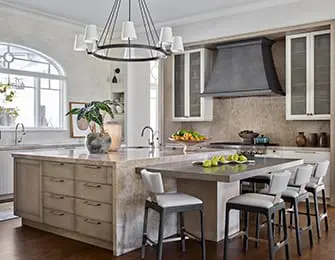 Kitchen island with seating, marble countertops, and custom cabinetry. Light gray island stools.