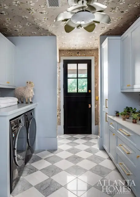 Light blue laundry room with floral wallpaper, black door, and marble tile floor.