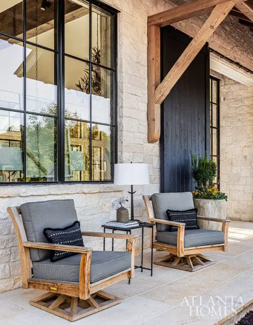 Two gray upholstered swivel chairs with wooden frames on a stone patio.