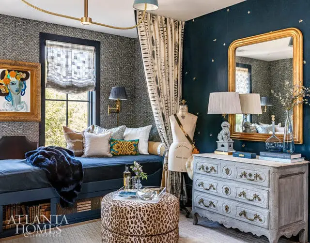 Blue daybed with pillows, leopard print ottoman, and gray dresser with gold mirror