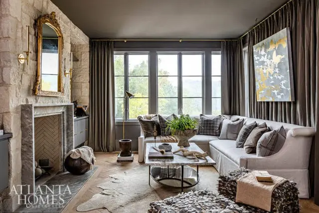 Living room with stone fireplace, sectional sofa, marble coffee table, and artwork of birds.