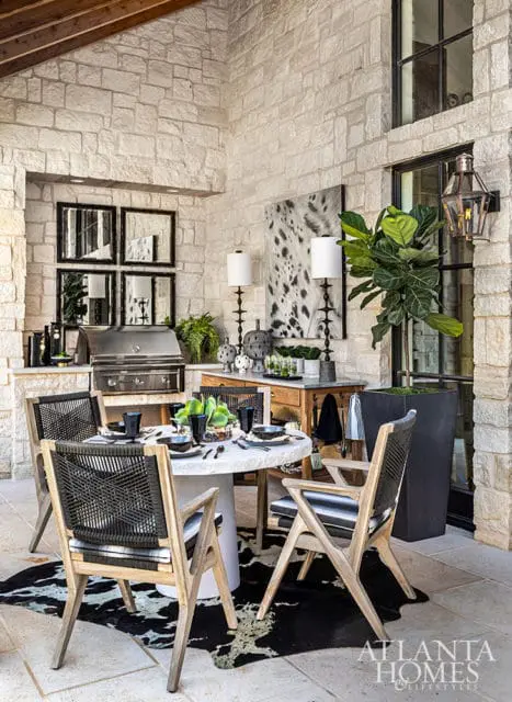 Outdoor dining area with stone walls, built-in grill, round table, and chairs