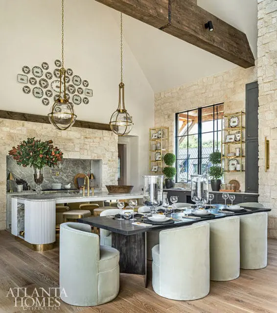 Dining area with stone walls, vaulted ceiling, and pendant lights. Table set for dinner.
