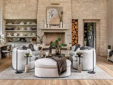 Living room with stone walls, fireplace, plush seating, and large ottoman