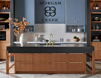Modern kitchen with dark island, wood cabinetry, and blue uppers.
