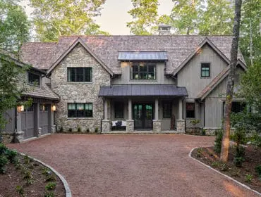 Stone and wood-sided house with dark metal roof and covered front porch.