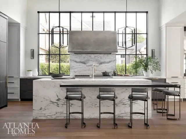 Modern kitchen with marble island, gray bar stools, and large window.