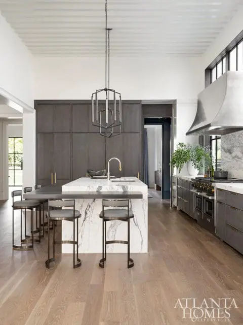 Modern kitchen with dark gray cabinetry, marble island, and pendant light.