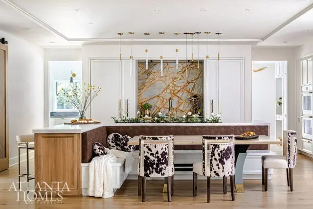 Modern kitchen with marble backsplash, cowhide chairs, and wood cabinetry.
