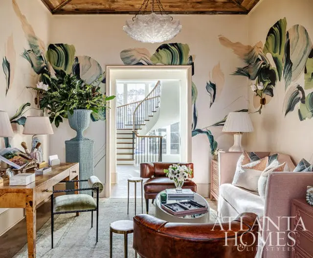 Living room with abstract floral wallpaper, leather chairs, and a pink sofa.