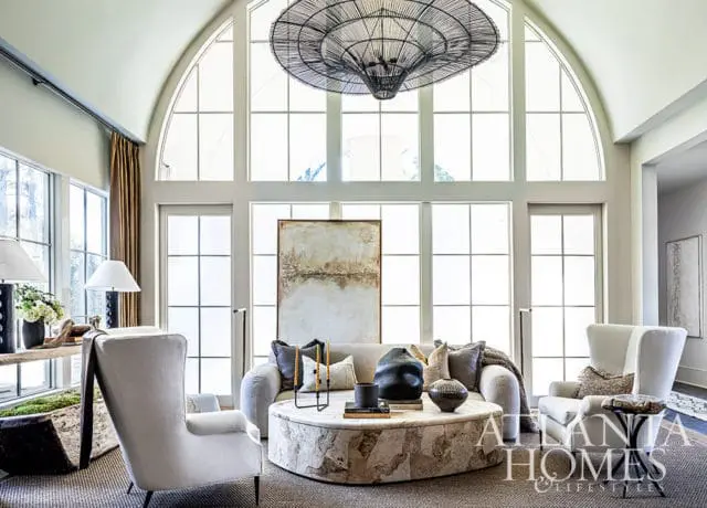 Living room with arched window, neutral sofa, stone coffee table, and large abstract art.