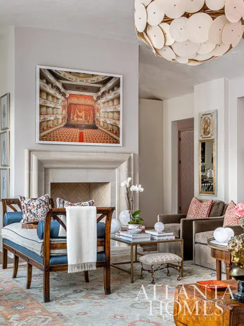 Living room with fireplace, artwork of a theater, and seating area with patterned pillows