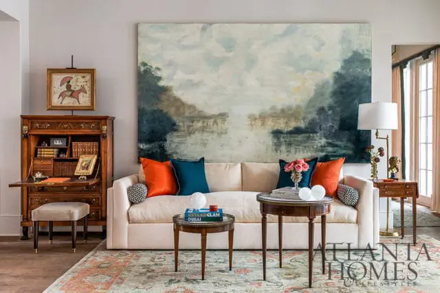 Living room with cream sofa, large abstract landscape painting, antique secretary desk, and ornate
