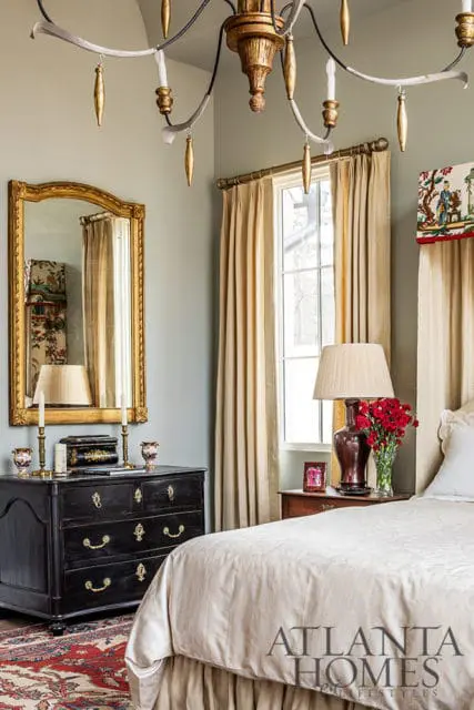 Bedroom with a black dresser, gold mirror, and beige curtains.