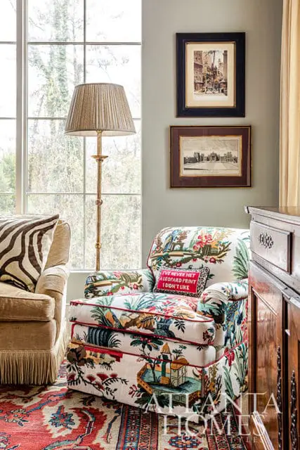 Armchair with floral print upholstery, red piping, and a leopard print pillow with text.