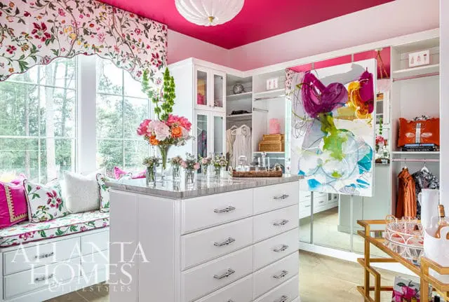 Walk-in closet with white cabinetry, marble island, floral window seat, and abstract art.