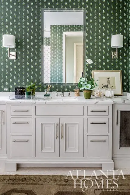 Bathroom vanity with gray cabinets, marble countertop, and green floral wallpaper.