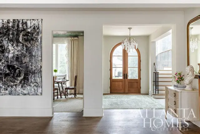 Entryway with arched double doors, crystal chandelier, and staircase.