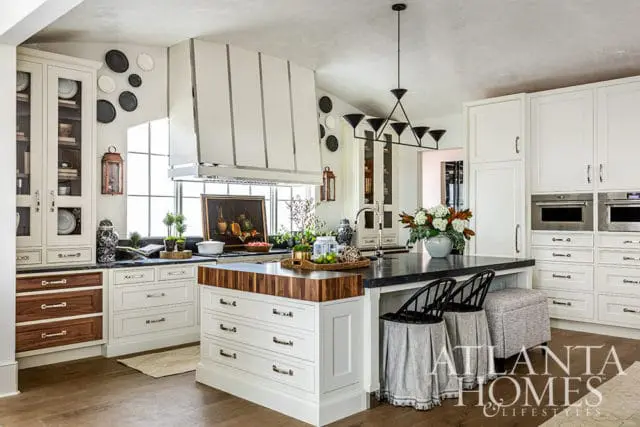 White kitchen with wood island, black countertops, and pendant lighting.