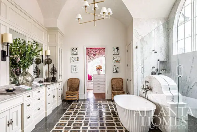 White bathroom with vaulted ceiling, marble shower, freestanding tub, and patterned floor