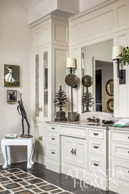 Cream vanity with marble countertop, mirrored cabinets, and brass hardware.