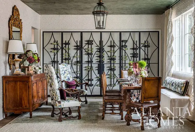 Dining room with ornate wine rack, floral upholstered chairs, and antique wooden furniture.
